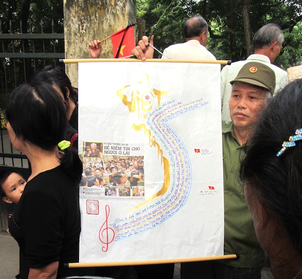 An officer holds a poster commemorating General Giap on Hoang Dieu, Hanoi on Sunday.
